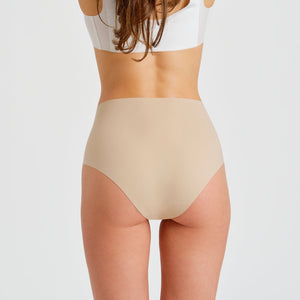 Modell trägt ooia everyday Highwaist Seamless in Beige – nahtlose Unterwäsche mit hohem Bund, die Slipeinlagen ersetzt. Rückansicht.