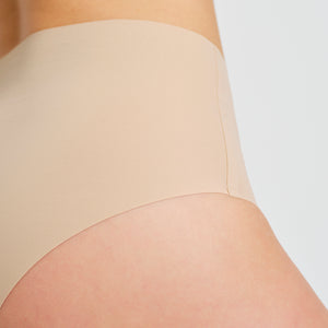Modell trägt ooia everyday Highwaist Seamless in Beige – nahtlose Unterwäsche mit hohem Bund, die Slipeinlagen ersetzt. Detailansicht.