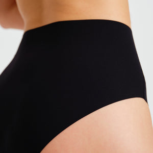 Modell trägt ooia everyday Highwaist Seamless in Schwarz – nahtlose Unterwäsche mit hohem Bund, die Slipeinlagen ersetzt. Detailansicht.