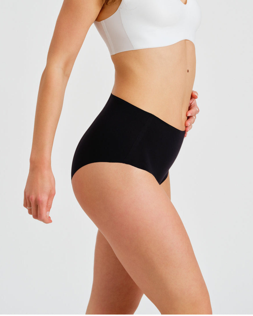 Modell trägt ooia everyday Highwaist Seamless in Schwarz – nahtlose Unterwäsche mit hohem Bund, die Slipeinlagen ersetzt