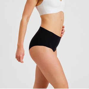 Modell trägt ooia everyday Highwaist Seamless in Schwarz – nahtlose Unterwäsche mit hohem Bund, die Slipeinlagen ersetzt