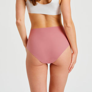 Modell trägt ooia everyday Highwaist Seamless in Dusky Pink – nahtlose Unterwäsche mit hohem Bund, die Slipeinlagen ersetzt. Rückansicht.