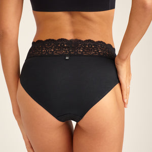 Modell trägt ooia everyday Slip in Schwarz – Unterwäsche mit breitem Spitzenbund, die Slipeinlagen ersetzt. Rückansicht.