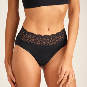 Modell trägt ooia everyday Slip in Schwarz – Unterwäsche mit breitem Spitzenbund, die Slipeinlagen ersetzt.