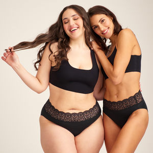 Zwei Models unterschiedlicher kOnfektion tragen ooia everyday Slip in Schwarz – Unterwäsche mit breitem Spitzenbund, die Slipeinlagen ersetzt.