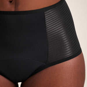 Modell trägt ooia Highwaist Extra Strong in Schwarz – Periodenunterwäsche mit hohem Bund und Glanzdetail. Detailansicht.