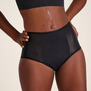 Modell trägt ooia Highwaist Extra Strong in Schwarz – Periodenunterwäsche mit hohem Bund und Glanzdetail.