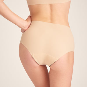 Modell trägt ooia Highwaist Seamless in Beige – nahtlose Periodenunterwäsche mit hohem Bund. Rückansicht.