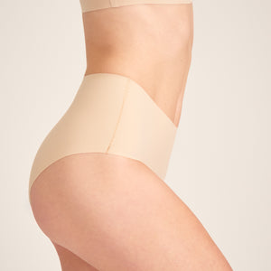 Modell trägt ooia Highwaist Seamless in Beige – nahtlose Periodenunterwäsche mit hohem Bund.