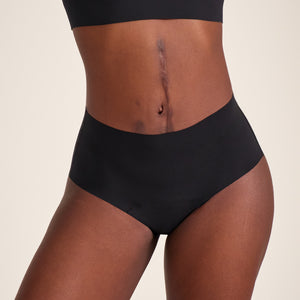 Modell trägt ooia Highwaist Seamless in Schwarz – nahtlose Periodenunterwäsche mit hohem Bund.