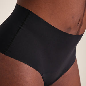Modell trägt ooia Highwaist Seamless in Schwarz – nahtlose Periodenunterwäsche mit hohem Bund.