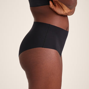 Modell trägt ooia Highwaist Seamless in Schwarz – nahtlose Periodenunterwäsche mit hohem Bund.