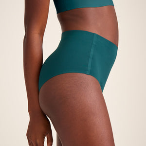 Modell trägt ooia Highwaist Seamless in Grün – nahtlose Periodenunterwäsche mit hohem Bund.