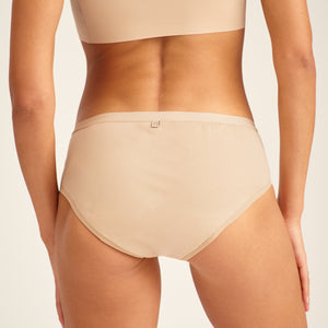 Modell trägt ooia Hipster in Beige – Periodenunterwäsche. Rückansicht.