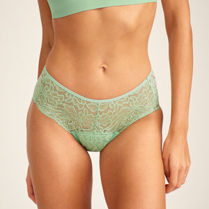 Modell trägt ooia Hipster Allover Lace in Bright Sage – Periodenslip mit durchgehender floraler Spitze