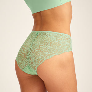 Modell trägt ooia Hipster Allover Lace in Bright Sage – Periodenslip mit durchgehender floraler Spitze