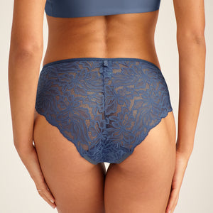 Modell trägt ooia Hipster Allover Lace in Smoky Blue – elegante Periodenunterwäsche mit durchgehender Spitze. Rückansicht.