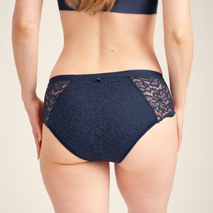 Modell trägt ooia Hipster Allover Lace Extra Strong in Midnight – Periodenunterwäsche mit floraler Spitze und extra hoher Saugkraft. Rückansicht.