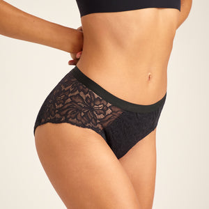 Modell trägt ooia Hipster Allover Lace Extra Strong in Schwarz - Periodenunterwäsche mit durchgehender Spitze und starker Saugstärke.