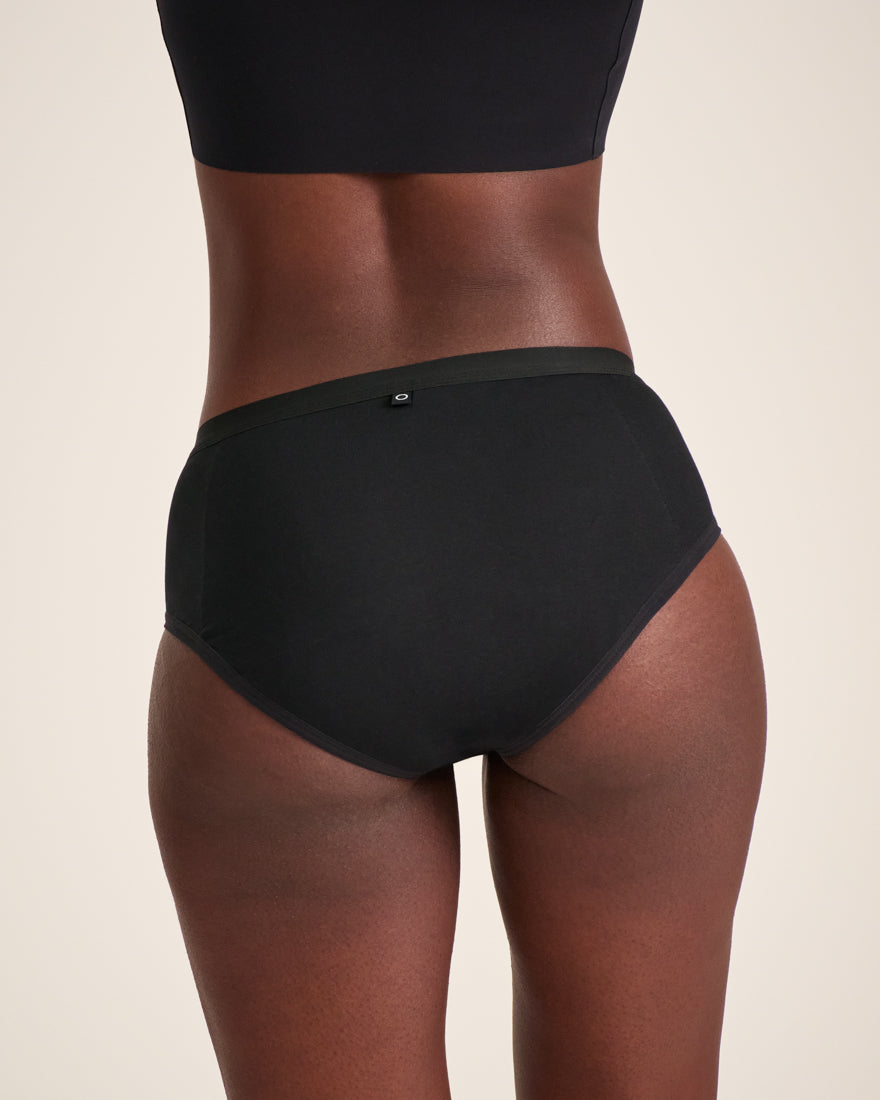Modell trägt ooia Hipster Extra Strong in Schwarz – Periodenunterwäsche im klassischen Schnitt, mit starker Saugstärke. Rückansicht.