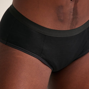 Modell trägt ooia Hipster Extra Strong in Schwarz – Periodenunterwäsche im klassischen Schnitt, mit starker Saugstärke. Detailansicht.