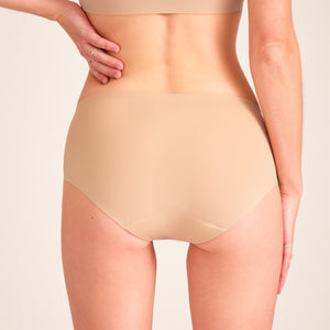 Modell trägt ooia Hipster Seamless in Beige – nahtlose Periodenunterwäsche. Rückansicht.