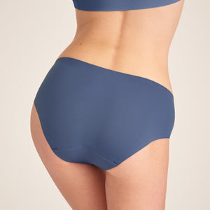 Modell trägt ooia Hipster Seamless in Smoky Blue – nahtlose Periodenunterwäsche. Rückansicht.
