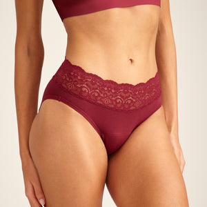 Modell trägt ooia Periodenunterwäsche Slip in Merlot, mit breiter Spitze am Bund