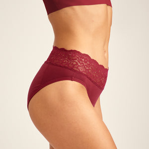 Modell trägt ooia Periodenunterwäsche Slip in Merlot, mit breiter Spitze am Bund