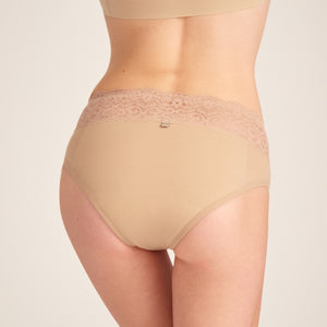 Modell trägt ooia Slip in Beige - Periodenunterwäsche mit breitem Spitzenbund im klassischen Schnitt. Rückansicht.