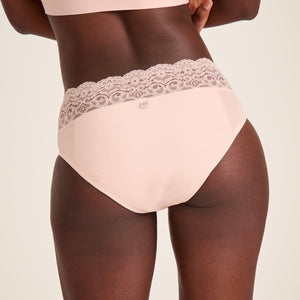 Modell trägt ooia Slip in Powder Rose - Periodenunterwäsche mit breitem Spitzenbund. Rückansicht.
