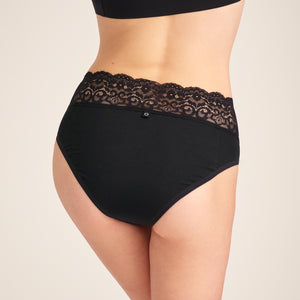 Modell trägt ooia Slip in Schwarz – Periodenslip mit breitem Spitzenbund im klassischen Schnitt. Rückansicht.