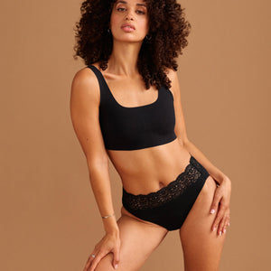 Modell trägt ooia Slip in Schwarz – Periodenslip mit breitem Spitzenbund im klassischen Schnitt.