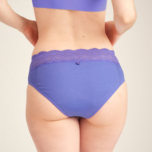 Modell trägt ooia Slip Extra Strong in Lilac - ooia Periodenslip mit breitem Spitzenbund. Rückansicht.