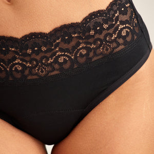 Modell trägt ooia Slip Extra Strong in Schwarz – Periodenunterwäsche mit breitem Spitzenbund im klassischen Schnitt. Detailansicht.