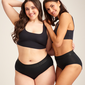 Zwei Models tragen ooia Slip Hugs Extra Strong in Schwarz – bequemer Slip mit extra stützendem Bund, starker Sauglstärke und integrierten Taschen für das ooia Wärmepad.