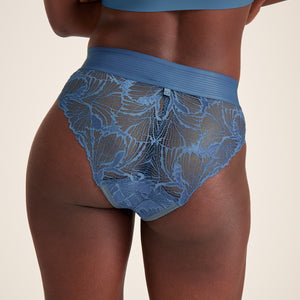 Modell trägt ooia Slip Lace Leaf in Smoky Blue – eleganter Slip mit durchgehender Spitze und breitem Bund. Rückansicht.