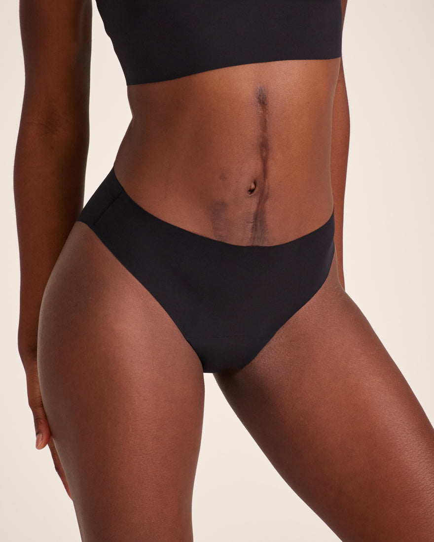 Modell trägt ooia Slip Seamless in Schwarz – nahtlose Periodenunterwäsche im klassischen Schnitt.