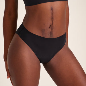 Modell trägt ooia Slip Seamless in Schwarz – nahtlose Periodenunterwäsche im klassischen Schnitt.