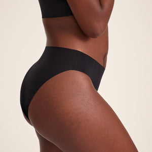 Modell trägt ooia Slip Seamless in Schwarz – nahtlose Periodenunterwäsche im klassischen Schnitt.