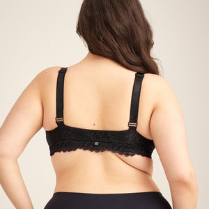 Modell trägt ooia Moms Still-BH Lace in Schwarz – eleganter Still-BH, der Stilleinlagen ersetzt. Rückansicht.