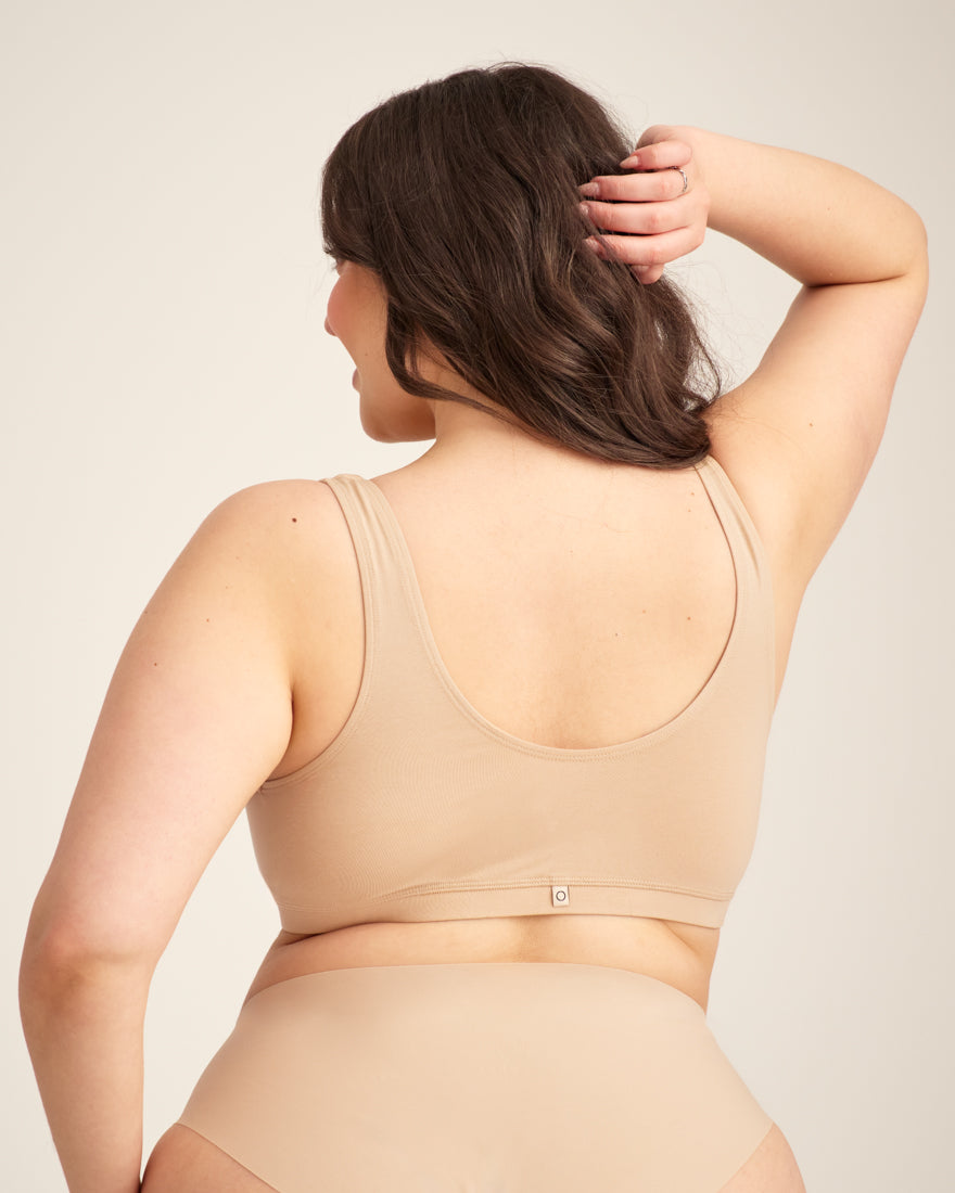 Modell trägt ooia Moms Still-BH in Beige – Still-BH ersetzt Stilleinlagen mit praktischer Pull-Down Funktion. Rückansicht.