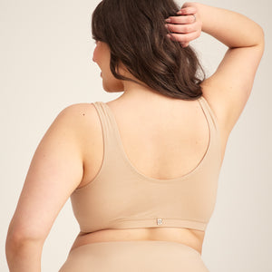 Modell trägt ooia Moms Still-BH in Beige – Still-BH ersetzt Stilleinlagen mit praktischer Pull-Down Funktion. Rückansicht.