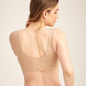 Modell trägt ooia Moms Still-BH in Beige – Still-BH ersetzt Stilleinlagen mit praktischer Pull-Down Funktion. Rückansicht.