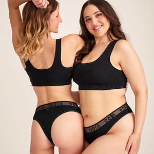 Zwei Models unterschiedlicher Konfektion tragen ooia Brazilian in Schwarz – Periodenunterwäsche mit breitem Mash-Bund mit ooia Logo.