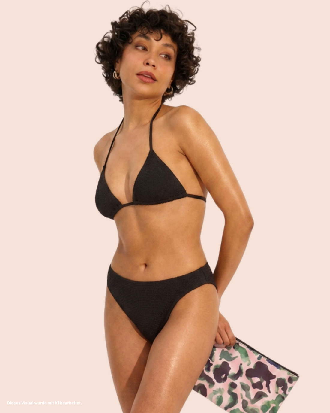 Model präsentiert ooia Perioden-Beachwear Shiny Bikini in glowing black. Plus Wetbag.
