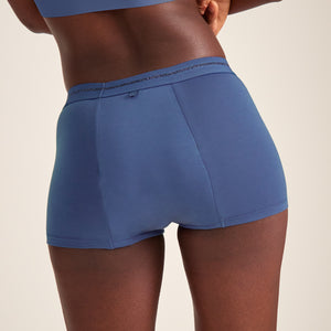 Modell trägt ooia Shorty Extra Strong in Blaubeere – bequeme Periodenshorts mit starker Saugstärke. Rückansicht.