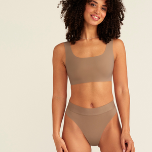 Modell trägt ooia Periodenslip Seamless Cheeky in Taupe mit hohem Beinausschnitt
