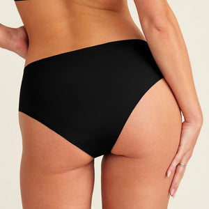 Modell trägt ooia everyday Hipster Seamless in Schwarz - nahtlose Unterwäsche die Slipeinlagen ersetzt. Rückansicht.