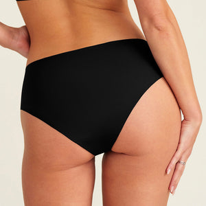 Modell trägt ooia everyday Hipster Seamless in Schwarz – nahtlose Unterwäsche, die Slipeinlagen ersetzt. Rückansicht.